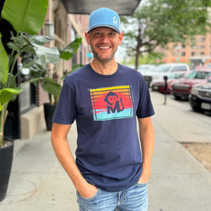 Front view of a man wearing the Ocean Sunset Graphic Tee outside a downtown restaurant