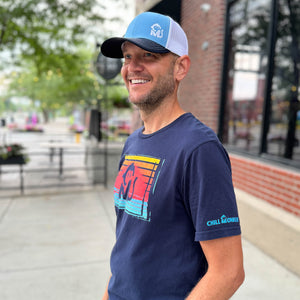 Side view of a man wearing the Ocean Sunset Graphic Tee outside a downtown restaurant