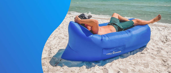 Man relaxing on a beach in a royal blue Chill Monkee inflatable lounger