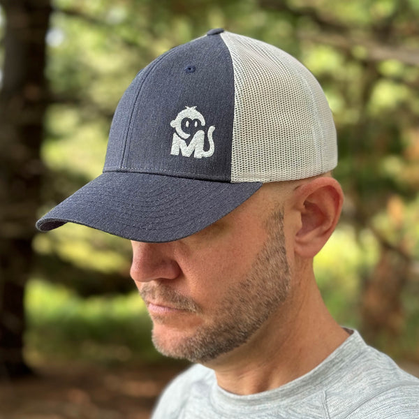 Front view of a man wearing the Iconic Monkee Low Pro Trucker Hat in navy heather and light grey