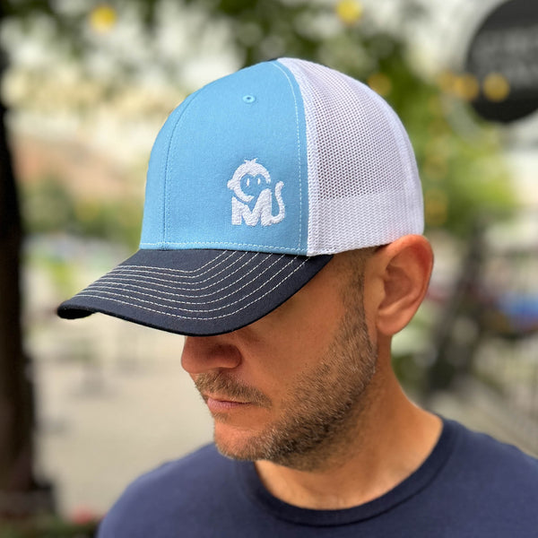 Front view of a man wearing the Iconic Monkee Mid Pro Trucker Hat in Columbia blue, white, and navy