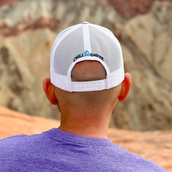 Rear view of a man wearing the Iconic Monkee Mid Pro Trucker Hat in heather grey and white while hiking