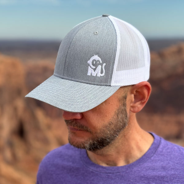 Front view of a man wearing the Iconic Monkee Mid Pro Trucker Hat in heather grey and white while hiking