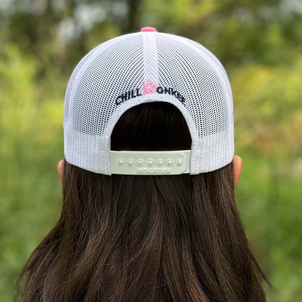 Rear view of a woman wearing the Iconic Monkee Mid Pro Trucker Hat in hot pink and white