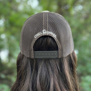 Rear view of a woman wearing the Iconic Monkee Multicam Trucker Hat in original and coyote brown