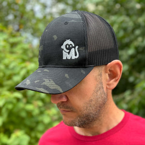 Front view of a man wearing the Iconic Monkee Multicam Trucker Hat in black and black