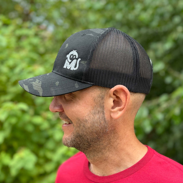 Side view of a man wearing the Iconic Monkee Multicam Trucker Hat in black and black