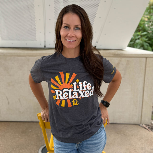 Front view of a woman wearing the Life Relaxed Sunburst Graphic Tee at a city park