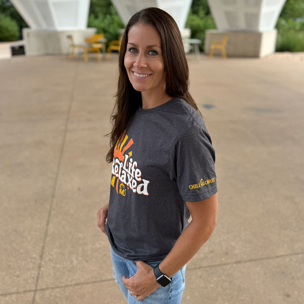 Side view of a woman wearing the Life Relaxed Sunburst Graphic Tee at a city park