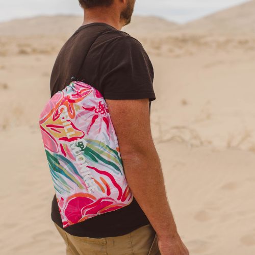 Man carrying a floral patterned Chill Monkee inflatable lounger slung over his shoulder