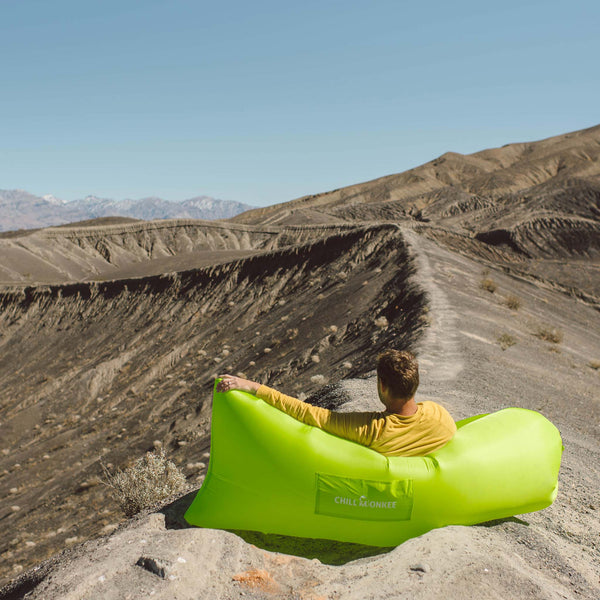 Man relaxing in a lime green Chill Monkee inflatable lounger during a hike