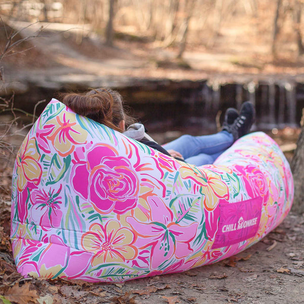 Woman relaxing next to a waterfall in a floral-patterned Chill Monkee inflatable lounger