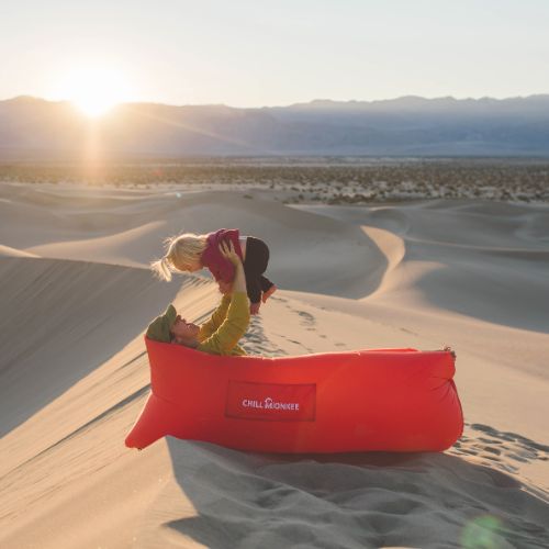 Mother laying in a red Chill Monkee inflatable lounger with her daughter in the desert