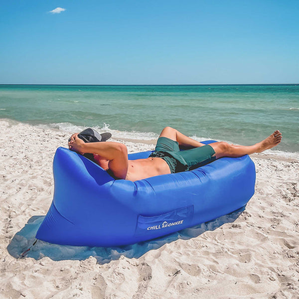 Man lying on a Chill Monkee Royal Blue Lazy Lounger on the beach.